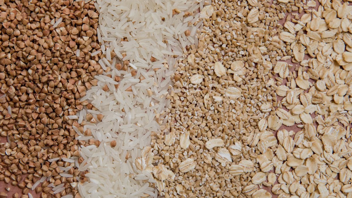 A variety of grains and cereals including oats, rice, and buckwheat arranged in a flat lay.